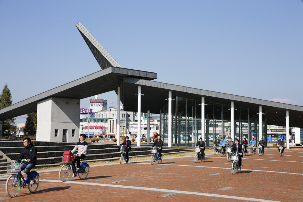 영남대 천마지문 앞에서 공공자전거를 타고 있는 이효수 총장과 영남대생들.jpg